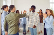 © Studio Romantic - Diverse group of friends standing in a circle during meeting, expressing success. With smiles they engage in handshake or high five, creating a symbol of collaboration and teamwork.
