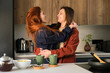 © Cavan Images - Lesbian happy couple hugging in love together in kitchen.