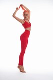 Fototapeta  - Confident sporty woman in red active wear standing with raised arms