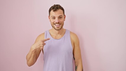 Sticker - Spirited young man in a sleeveless t-shirt beaming joyfully, confidently pointing with finger over isolated pink background