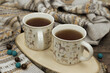Two mugs of hot tea surrounded by a warm sweater. Hot tea and warm clothes create a cozy atmosphere. A hot drink will warm you up during the cold season.