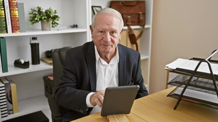 Sticker - Confident and joyful senior man, a memorable boss with white hair, happily works online using touchpad at his elegant office desk, radiating success with every smile.