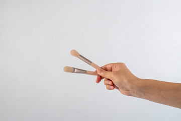 Wall Mural - Cosmetic brushes in hand on white background. Set of makeup brushes