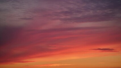Wall Mural - An abstract background of red-orange clouds in the dark evening sky, abstract timelapse