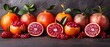   A collection of oranges, pomegranates, and foliage on a dark-colored surface