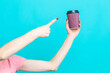 Closeup of Female Girl Hand Pointing with Finger Cup of Coffee Drink Isolated on Vivid Trendy Turquoise