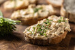 Close-up of bread slice with traditional Slovak bryndza spread made of sheep cheese with freshly cut chives placed on rustic wood