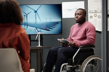 Aufkleber - Young African American man with disability sitting in wheelchair by interactive board with windmills on screen during presentation