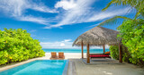 Fototapeta Zachód słońca - Tropical relax, outdoor tourism landscape. Luxury beach resort with private swimming pool and beach chairs canopy under umbrellas palm trees, sunny blue sky. Summer travel and vacation background