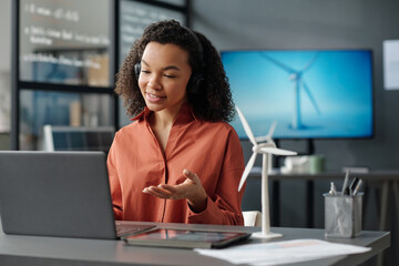 Aufkleber - Young smiling female employee explaining something to person during communication in video chat while sitting in front of laptop