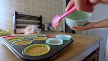 Woman’s Hands With Silicone Spatula Pouring Remaining Cupcake Batter Into Mold