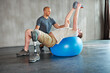 © peopleimages.com - Patient with disability, physiotherapist and help with kettlebell for stretching at gym for recovery, strength and healthcare rehabilitation. Physiotherapy, coach and client for support with exercise