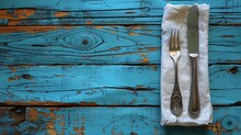 Table Setting. Cutlery. Fork, Knife In A White Napkin On A Blue Wooden Table. Top View