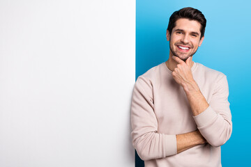 Wall Mural - Photo of sweet thoughtful man wear beige sweatshirt arm chin poster empty space isolated blue color background