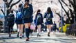 桜の下を歩いて学校へ向かう女子高生達