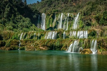 Wall Mural - View of the Jiulong waterfall streaming down to a lake