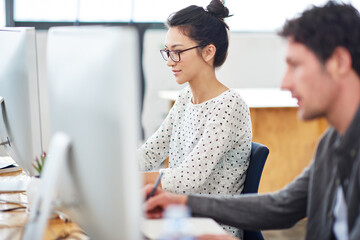 Canvas Print - Woman, man and working at agency with technology for internet, planning and profession. Employees, computer and together for editing in workplace with teamwork, graphic design and writing notes