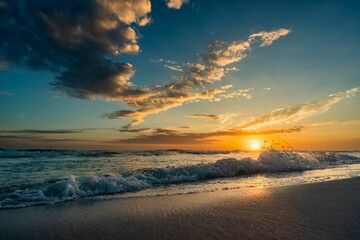 Wall Mural - an ocean and some clouds over the shore and a sunset