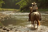 Fototapeta  - Cowgirl riding a palomino horse across a river in the countryside