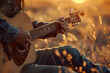 Man playing guitar in the serene countryside during a golden sunset