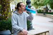 © Taras Grebinets - Caucasian young man drinking water from a sports bottle in the city