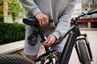 © Taras Grebinets - Close-up guy adjusting the height of new battery powered bike, electric bicycle before taking it out for the first ride.