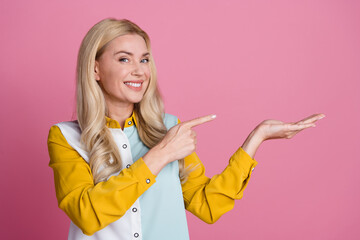 Poster - Photo of stunning cheerful person beaming smile indicate finger hand hold empty space isolated on pink color background