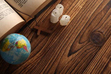 Wall Mural - Bible book, candles and wooden Christian cross on a string, globe wooden table. Messianism, Religion, prayer, going to church concept