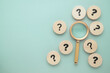© patpitchaya - Magnifying glass with many question marks round wood blocks, find the answer among many choices, research, and decision concept
