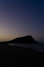 La Tejita Beach Sunrise In Blue Hour With The Silhouette Of The Hill, The Sand  And The Ocean