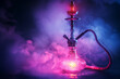 hookah with glass flask on black background of shisha smoke with neon light