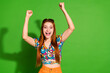 Photo portrait of attractive young woman raise fists winning dressed stylish retro clothes isolated on green color background