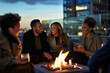 Group of friends having a barbecue party at rooftop with bonfire in the background
