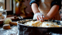 A Child In An Apron In The Kitchen Kneads Dough In A Large Basin.