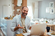 © Davor - Smiling man having a video call on laptop in a home environment
