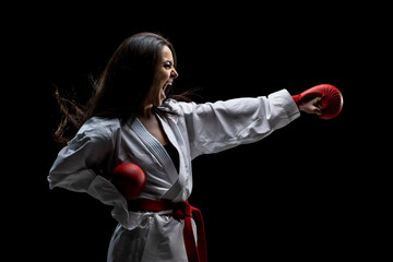 Wall Mural - girl exercising karate punch and screaming against black background