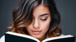 © Alexander - Young woman reading a book, close-up portrait, dark background