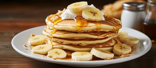 Wall Mural - A staple food dish made of pancakes topped with bananas and syrup, served on a white plate. Perfect for a breakfast event or brunch recipe