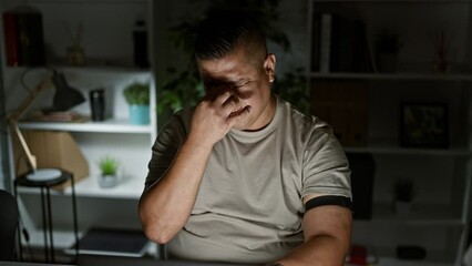 Sticker - Tired latin guy at dark office, working hard scanning smartphone over glucose sensor, measuring levels - young man's exhausting business world