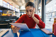 © Pedro Merino/Stocksy - Woman reading the menu at a breakfast spot