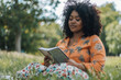 African American woman reading in a park, serene and relaxed.