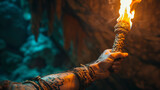Fototapeta  - A hand holding a lit torch in a cave.