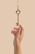 © Yaroslav Danylchenko/Stocksy - Close up of female hand reaching vintage key hanging on thread