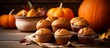 A variety of muffins are displayed on a table surrounded by pumpkins, showcasing a delicious combination of staple food and natural foods