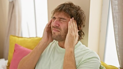 Wall Mural - Stressed young, handsome caucasian man suffering painful migraine hand-at-headache, all alone in his homey bedroom wearing pyjamas