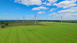 AERIAL: Rotating wind turbines rising above green pasture with grazing livestock