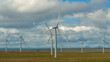 Spinning wind turbines in remote Scottish countryside beneath billowing clouds