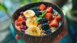 Nourishing smoothie bowl served in a coconut with creamy blend of berries, banana, yogurt, topped with fresh fruits, granola. Healthy breakfast, dessert vegan concept