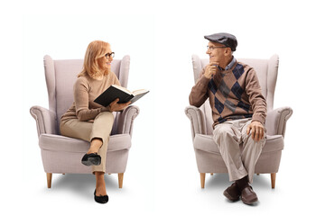 Wall Mural - Mature woman holding a book and talking to a man seated in an armchair
