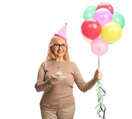 Middle aged woman holding a birthday cupcake and balloons